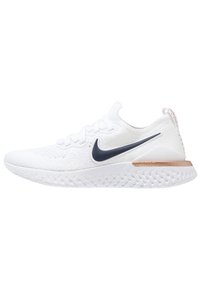 White Nike running shoe featuring a textured upper, navy swoosh logo, and a cushioned sole with a copper accent on the heel.
