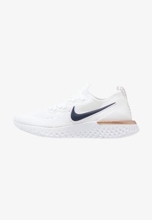 White Nike running shoe featuring a textured upper, navy swoosh logo, and a cushioned sole with a copper accent on the heel.
