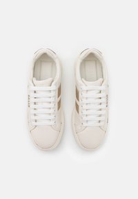 Białe skórzane sneakersy z beżowymi zamszowymi paskami, białymi sznurówkami i wytłoczonym logo na boku. Klasyczny niskoprofilowy design.