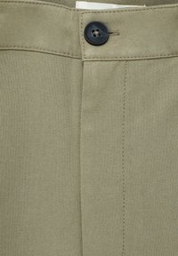 Olijfgroene broek met een knoopsluiting aan de voorkant, gladde stoftextuur en zichtbare stiksels langs de naad en tailleband.