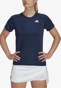 Marinblå kortärmad sportt-shirt med meshtyg, med en vit logotyp på vänster axel och rundad halsringning.