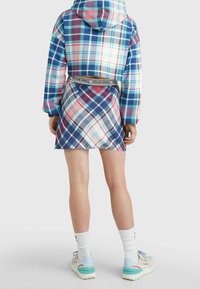 Felpa con cappuccio corta in plaid multicolore, abbinata a una gonna corrispondente con cintura. Presenta diverse tonalità di blu, rosa e modelli bianchi.