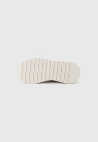 Semelle de basket blanche avec un motif ondulé et rainuré, conçu pour l'adhérence. Texture lisse, bout arrondi et talon légèrement rétréci.