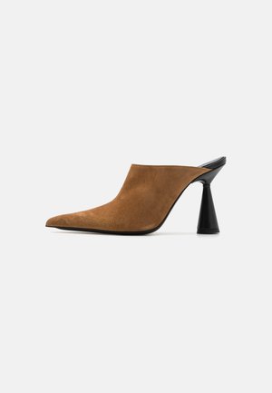 Brune ruskinds mule med spids tå og en sort geometrisk hæl, med en glat tekstur og minimalisk design.
