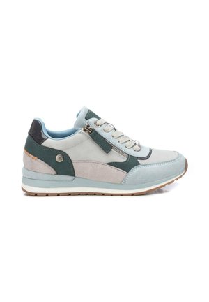 Zapatilla deportiva azul claro y gris con acentos verdes, cordones, cremallera lateral y una suela gruesa, mostrada desde el lado exterior sobre un fondo blanco.