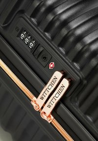 Czarna walizka twarda z teksturowaną powierzchnią, różowo-złotymi okuciami, zamkiem szyfrowym oraz podwójnymi suwakami z napisem "WITTCHEN".