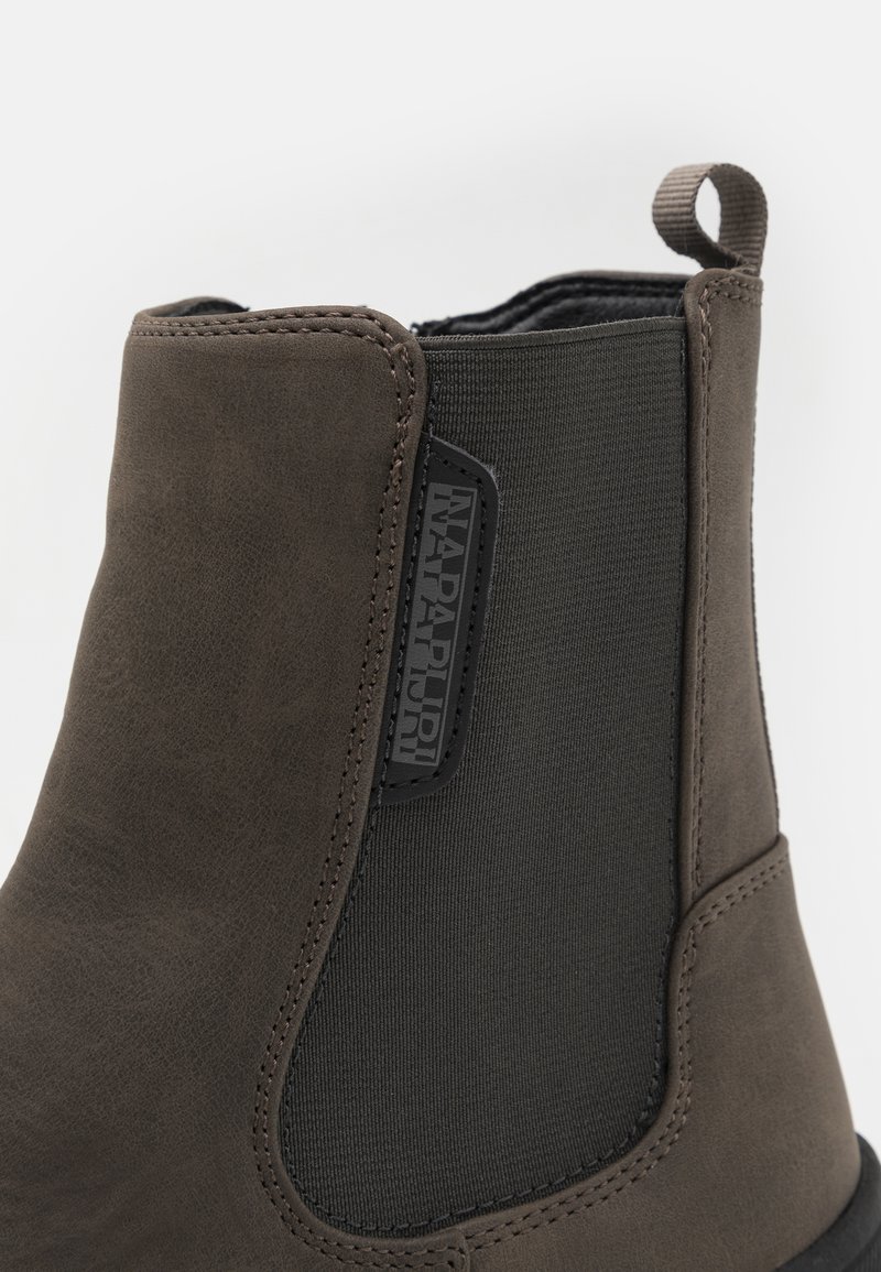 Bruine leren laars met elastische zijkanten, textuur oppervlak en gestikte details. Beschikt over een logo-label en een trekband voor gemakkelijk aan- en uittrekken.