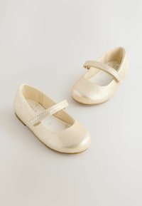 Gold faux leather Mary Jane shoes with textured finish, flat sole, and a wide strap across the instep. Rounded toe design.