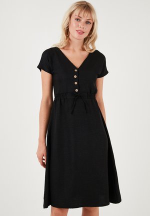 Black dress made of textured fabric, featuring a V-neck, short sleeves, front button detailing, and a cinched waist with a tie.