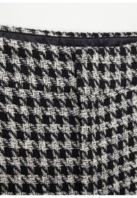 Tissu texturé pied-de-poule noir et blanc avec une bordure en satin noir le long du bord, montrant des détails en gros plan du matériau et du motif.