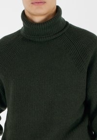 Maglione a collo alto lavorato a maglia di un verde scuro, con texture a coste e maniche raglan, dotato di un collo alto e dettagli di pattern sottili.