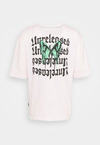 Hvid bomulds T-shirt med et stort grønt sommerfugle grafik og sort tekst, der siger "Udgivet" på ryggen. Løs pasform med korte ærmer.