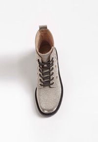 Bottine à lacets argentée pailletée avec semelle noire et lacets noirs, vue de dessus sur fond blanc.