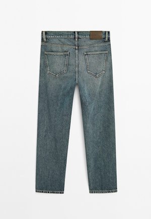 Gerade geschnittene blaue Jeans aus Denim, von hinten betrachtet, mit zwei Gesäßtaschen und einem braunen Markenpatch am Bund.