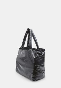 Borsa tote in pelle nera con una finitura in tessuto morbido e peloso nella parte superiore. Dotata di due manici robusti e una tasca laterale. Texture liscia e lucida.