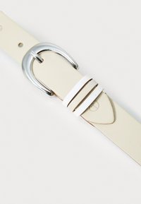 Leren riem in crème met zilveren gesp. Heeft een witte accentriem en een gladde textuur. Eenvoudig ontwerp met gaatjes voor aanpassing.