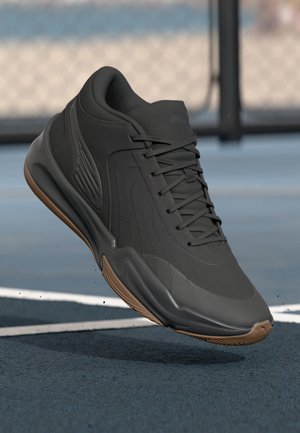 Chaussure de sport noire avec une tige en synthétique lisse, des accents texturés, et une semelle en caoutchouc naturel, conçue pour la performance et le confort.