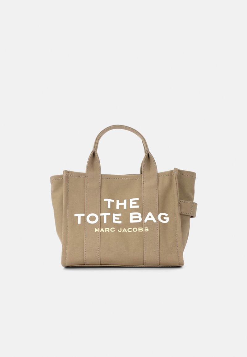 Borsa tote in tela color beige con due manici superiori. Presenta una grande scritta bianca "THE TOTE BAG" e "MARC JACOBS" stampata sul davanti. Forma rettangolare.