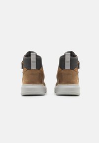 Botas de tobillo de ante marrón con acentos en textil gris y suela de goma. Incluyen un tirador en la parte posterior y un collar suave y acolchado.