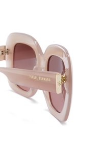 Übergroße Sonnenbrille mit einem transparenten, hellrosa Rahmen, braun getönten Gläsern und goldenen Akzenten an den Scharnieren und Bügeln.