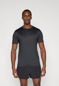 Μαύρο κοντομάνικο μπλουζάκι κατασκευασμένο από λείο ύφασμα που απομακρύνει την υγρασία. Διαθέτει στρογγυλή λαιμόκοψη και εφαρμόζει στενά στο σώμα.