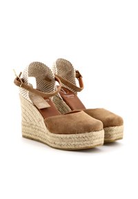Scarpe con zeppa in suede marrone, dotate di cinturini intrecciati alla caviglia e suole in corda. Texture liscia con punta arrotondata e soletta imbottita.