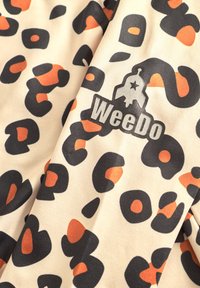 Leopardmönstrad tyg i beige med svarta och orange fläckar. Innehåller "WeeDo"-logon i grått, som är placerad framträdande inom mönstret.