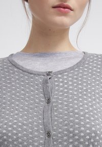 Grau gestrickte Strickjacke mit einem strukturierten Muster aus kleinen, erhabenen Punkten, fünf Knöpfen auf der Vorderseite und einem runden Halsausschnitt.