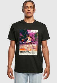 Sort bomulds T-shirt med et farverigt basketball-tema grafik og fede bogstaver. Designet inkluderer sprøjt af lilla og orange.