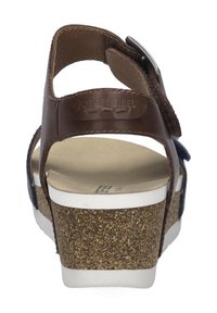 Braune Leder-Sandale mit verstellbarem Schnallenriemen, Korkwedge-Sohle und weißem Fußbett. Texturierte Details auf der Sohle sorgen für Grip.