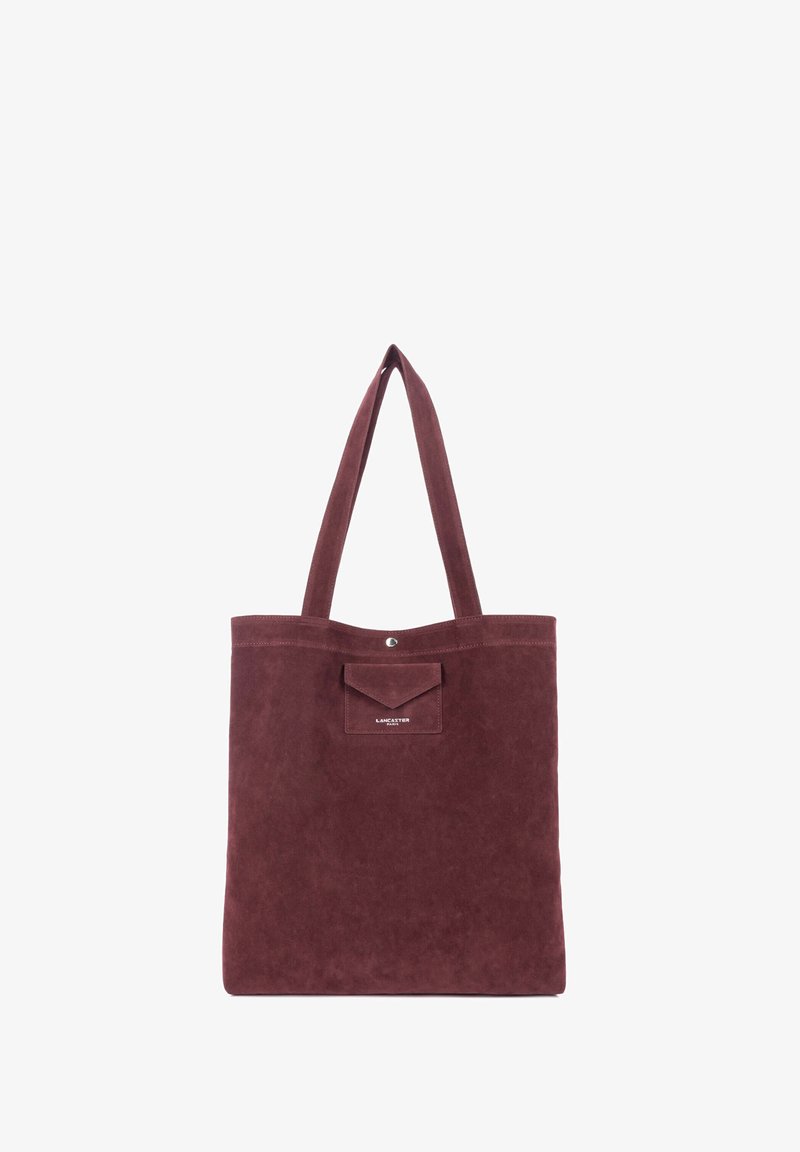 Sac cabas en suède rouge foncé avec de longues anses et une petite poche avant étiquetée Lancaster Paris.