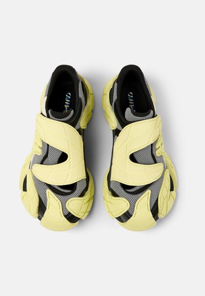 Black, gray, and neon yellow athletic shoes with a textured upper, featuring two padded straps and a thick sole with a geometric pattern.