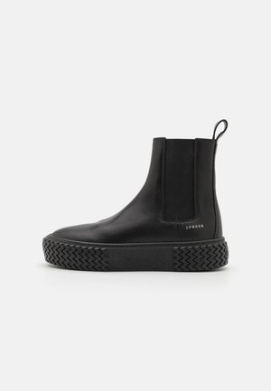 Schwarzer Chelsea-Lederstiefel mit dicker, strukturierter Sohle, elastischem Seitenteil, Zuglasche an der Ferse und kleinem "CPNHGN" Schriftzug an der Seite.