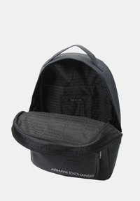 Zaino in ecopelle nera con superficie testurizzata, chiusura con zip e un interno spazioso foderato con un motivo di branding ripetuto.