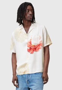 Camisa de manga corta en tela color crema claro con grandes estampados florales en naranja y amarillo pálido, con un bolsillo en el pecho y cierre de botones.
