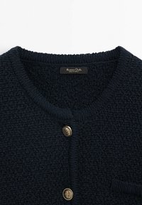 Dunkelblaue Strickjacke mit strukturiertem Finish, runder Halslinie, Knopfverschluss in Goldoptik und einer kleinen Tasche auf der Vorderseite.