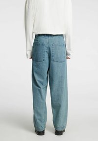 Svetlo modre široke kavbojke s širokimi hlačnicami, z dvema zadnjima žepoma, visokim pasom in sproščenim krojem. Material je videti mehak z gladko teksturo.