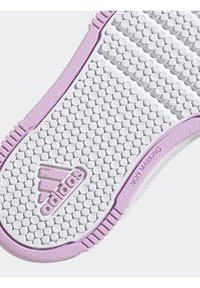 Biało-lawendowa elastyczna podeszwa buta z teksturowanym wzorem gripu; zawiera okrągłe wgłębienia oraz napis "NIE ZOSTAWIA ŚLADÓW". Obecne logo Adidas.