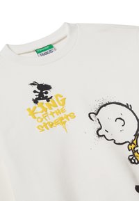 Felpa bianca con una grafica nera e gialla. Il design include un'illustrazione di un personaggio e il testo "RE DELLE STRADE."