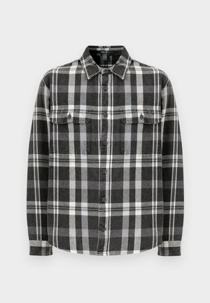 Camisa de flanela preta e branca em padrão xadrez, mangas longas, fecho com botões, dois bolsos no peito, textura suave, colarinho estruturado, barra reta.