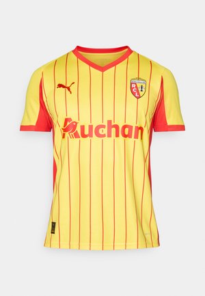 La camiseta de fútbol a rayas amarillas y rojas presenta el logotipo de Puma y el patrocinio de "Auchan", con el emblema del RCL en el lado izquierdo del pecho.