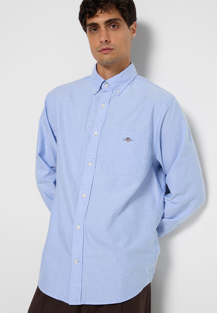 Jasnoniebieska koszula na guziki wykonana z bawełny. Posiada kieszeń na lewej piersi oraz małe logo. Długie rękawy z mankietami na guziki.