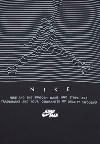 Černé tričko s horizontálními světle modrými pruhy a grafikou připomínající hory. Text zahrnuje bílé loga "NIKE" a "JUMP MAN".
