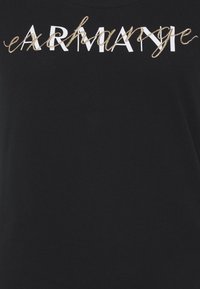 Zwart t-shirt met witte en gouden letters. De tekst combineert vette en cursieve stijlen, wat een textuurcontrast toevoegt.