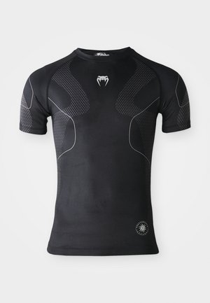 Schwarzes kurzärmliges Sportshirt mit strukturierten Einsätzen, dünnen weißen geschwungenen Linien, einem Fang-Logo auf der Brust und einem runden Performance-Abzeichen nahe dem Saum.