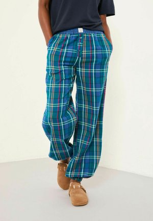 Blue plaid lounge pants made from soft fabric, featuring a loose fit, elastic waistband with buttons, and pockets. Paired with brown slippers.
