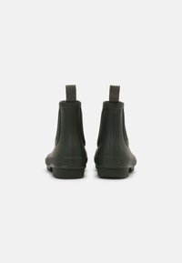 Bottes de cheville en caoutchouc vert avec texture à nervures verticales, bout rond et poignées à l'arrière pour un enfilage facile. Semelles plates pour plus de stabilité.