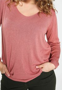 Top a maniche lunghe e scollo a V in rosa chiaro, realizzato in un tessuto a maglia testurizzato, con una vestibilità comoda e dettagli sulle cuciture laterali.