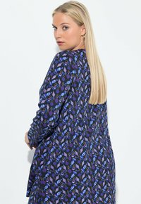 Pitkähihaisen tummansinisestä kankaasta valmistettu mekko, jossa on värikäs kuviolaatta abstrakteista muodoista ja pisteistä. Mekko on rento malli ja siinä on pehmeä textura.