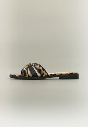 Lapos papucs leopárdmintával és fekete pántokkal, kis arany csattal, semleges háttér előtt fényképezve.